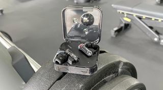 Nothing Ear in their charging case next to some weights at the gym