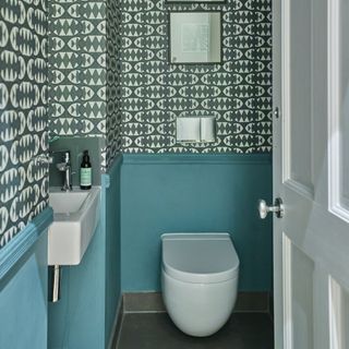 Downstairs toilet with teal wall panelling and dark green wallpaper