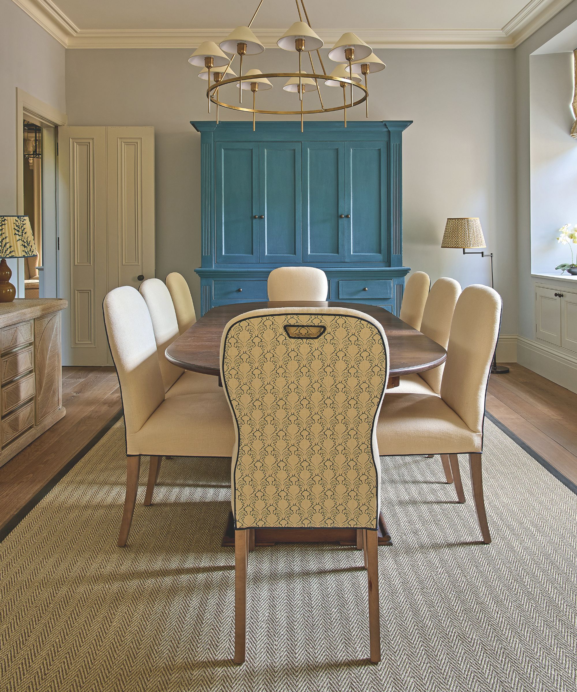 Pale gray dining room with large rug, large wooden table, statement blue dresser