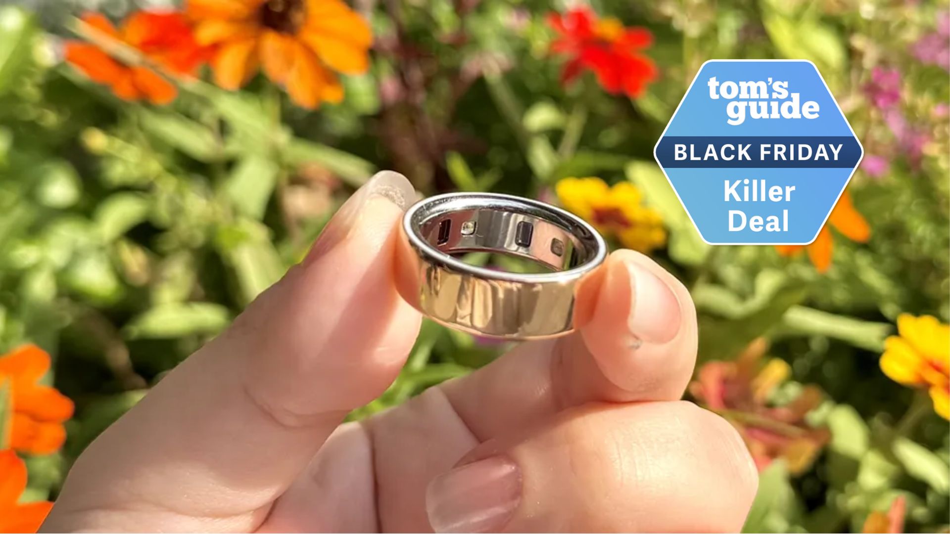 a hand holding the Oura Ring 4 next to a Tom's Guide Black Friday Killer Deal label