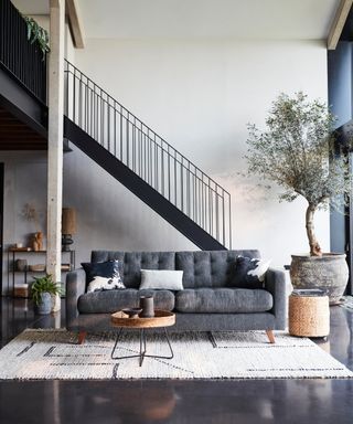 metal staircase in living room with grey concrete floor and grey sofas