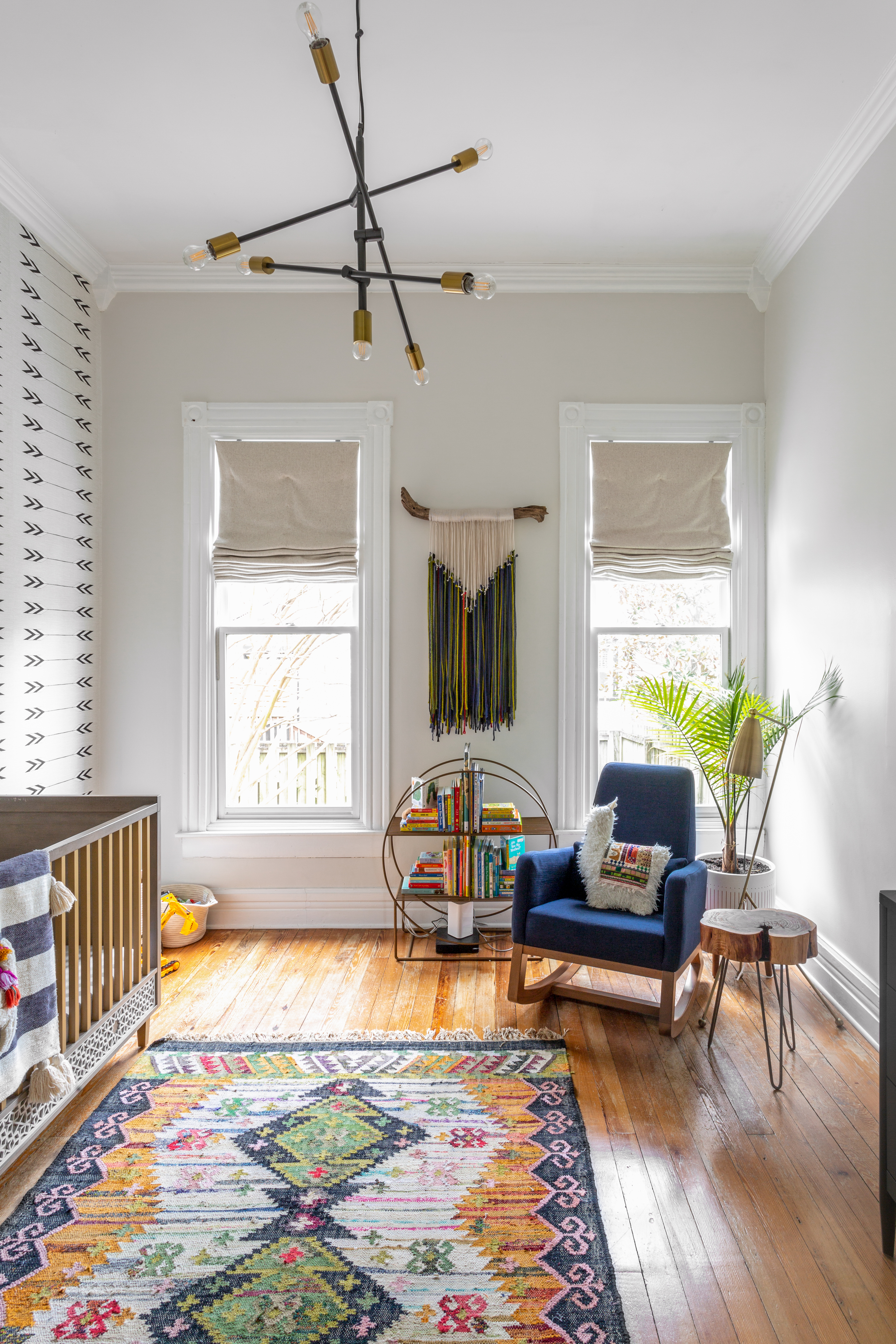 A nursery with a vibrant carpet and a blue chair, and large windows