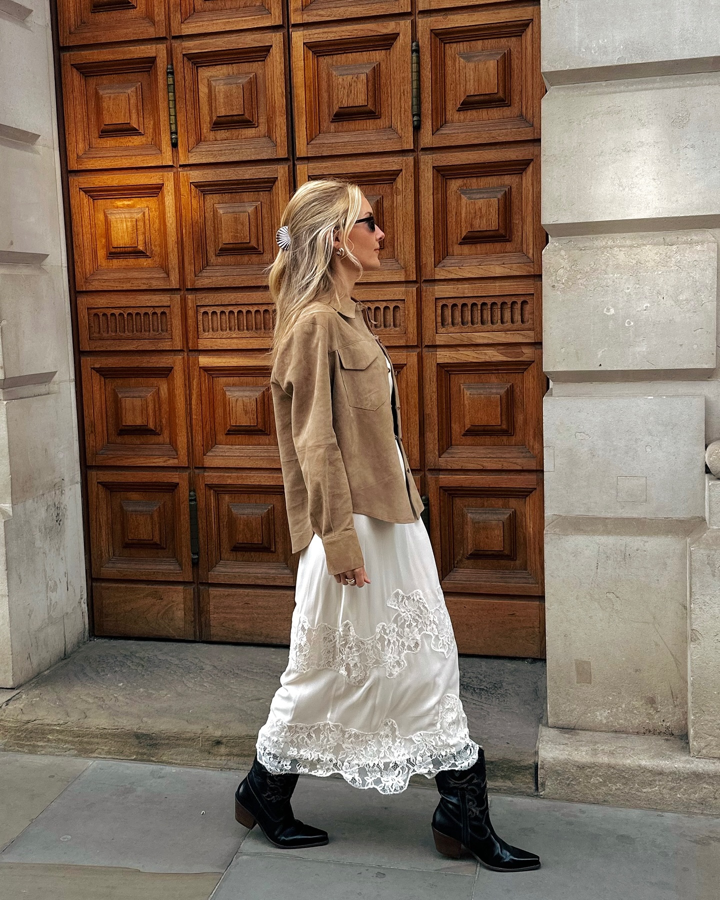 An image of @chloekathbutler wearing a lace maxi dress with ankle boots and a suede jacket.