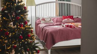 Image shows a colourful christmas tree with warm gold lights in a bedroom