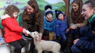 Kate Middleton and young children feeding a lamb