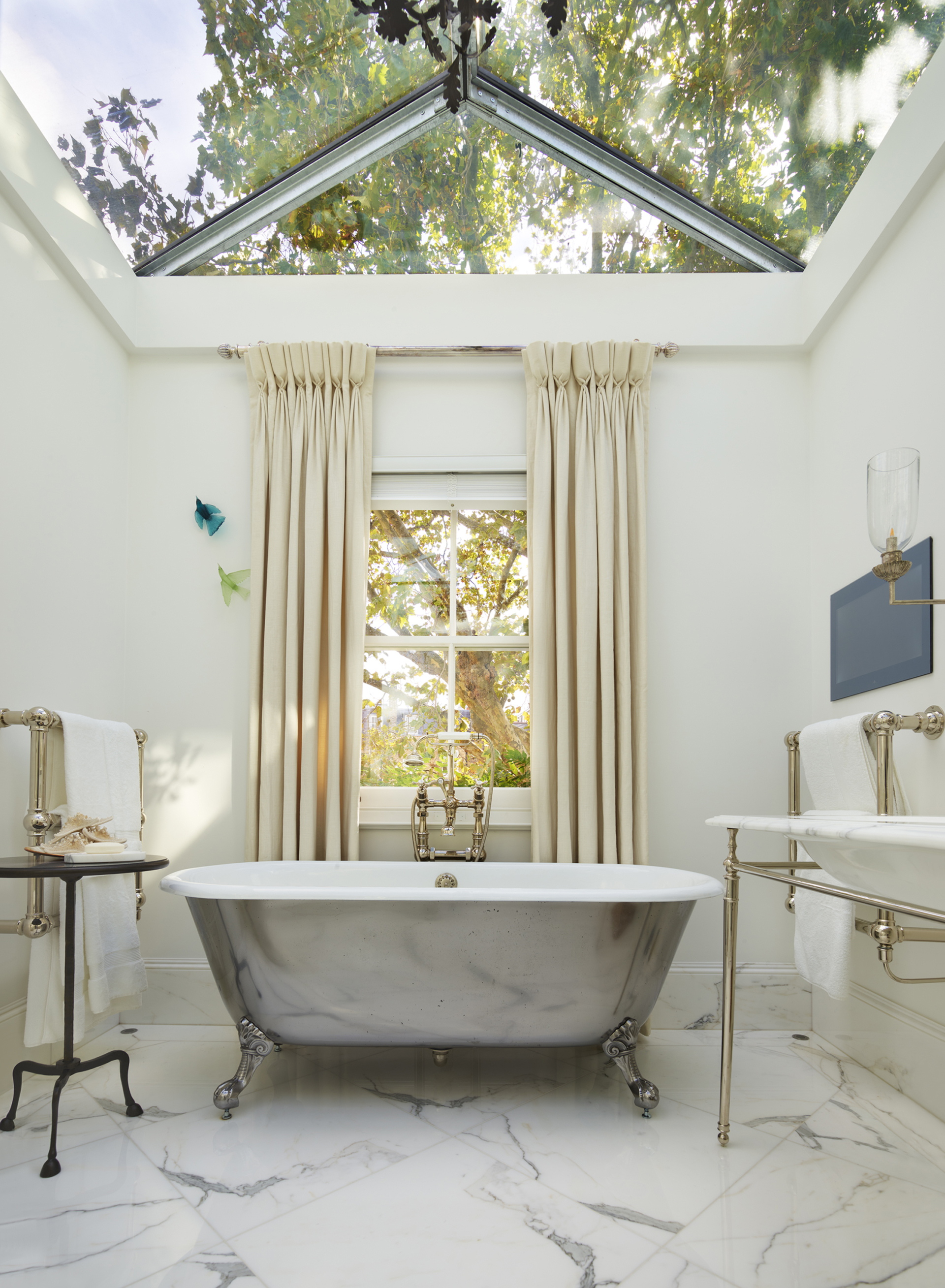 bathroom with skylight and window, marble floor and freestanding metallic bath in center