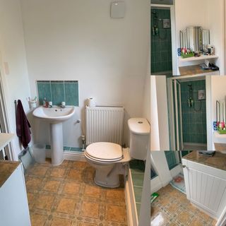 bathroom with white wall and washbasin and toilet and tiles flooring
