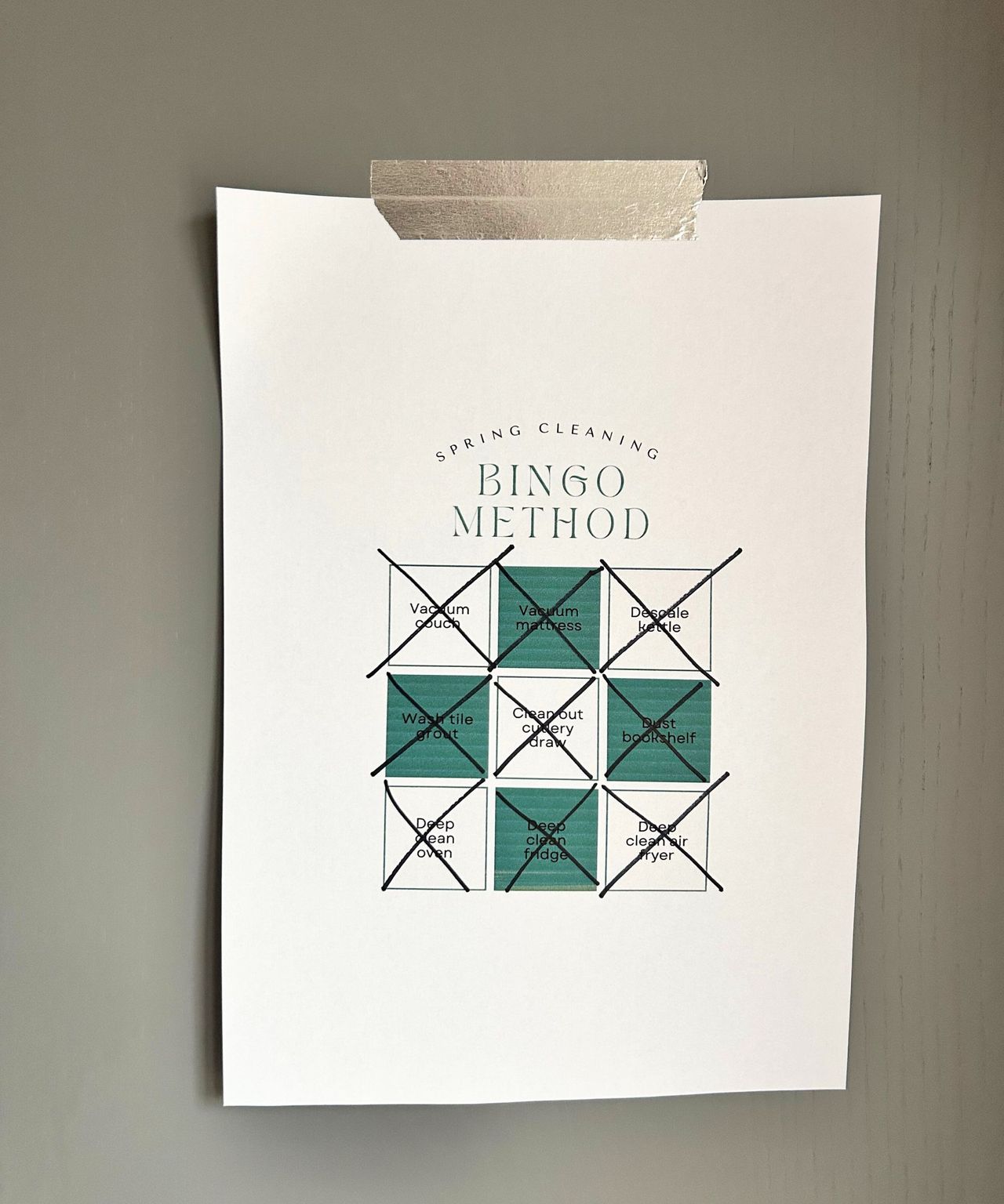 Spring Cleaning Bingo Method on white paper with green boxes and stuck up by silver washi tape