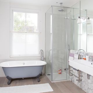 bathroom with wooden flooring and white bathtub and shower area