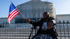 A demonstrator holds a US flag outside the US Supreme Court in Washington, DC, on Wednesday, Oct. 15, 2025