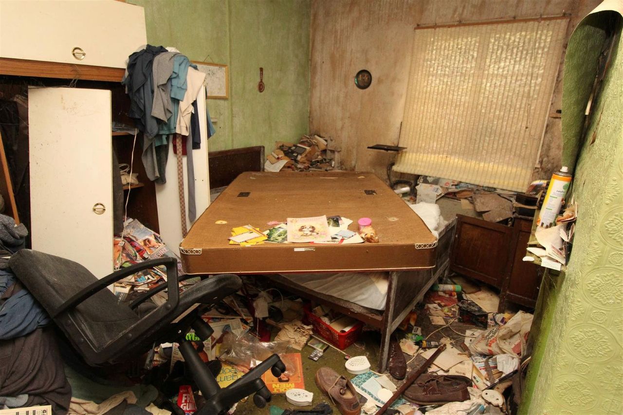 The study has a table with an old mattress on top of it as well as rubbish around with a broken chair