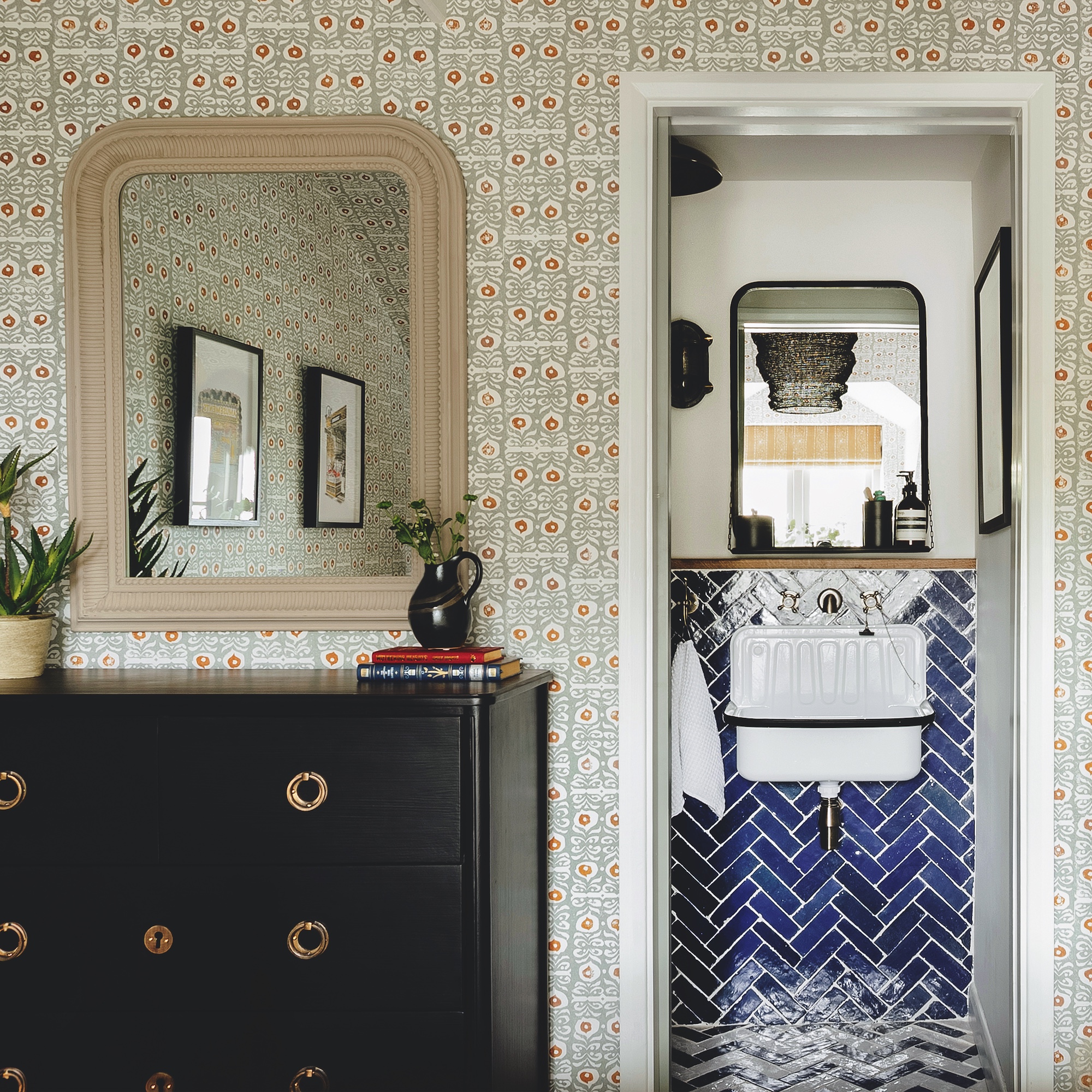 view from bedroom into small ensuite bathroom with blue herringbone wall and floor tiles and small enamel basin