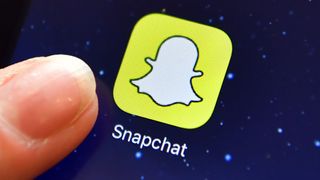A finger is posed next to the Snapchat app logo on an iPad.