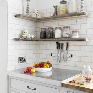 kitchen area with white wall tiles and plenty fruits with cupboard