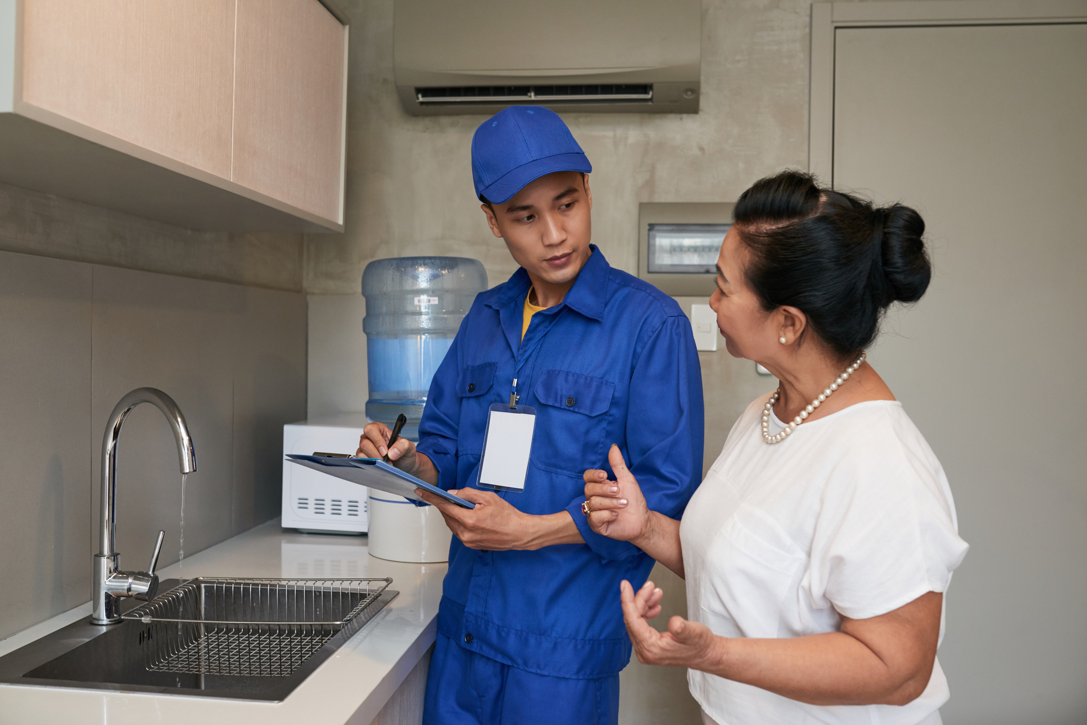 Woman talking to plumber in her kitchen