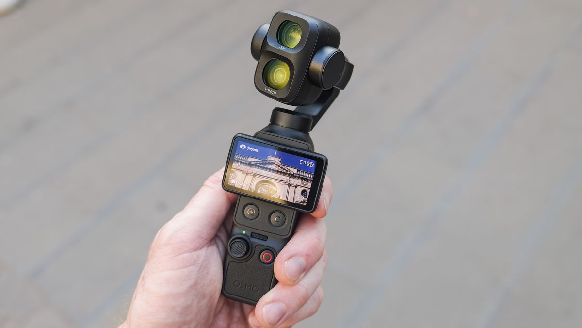 DJI Osmo Pocket 4P vlogging camera in a person's hand in a city street, screen rotated horizontal