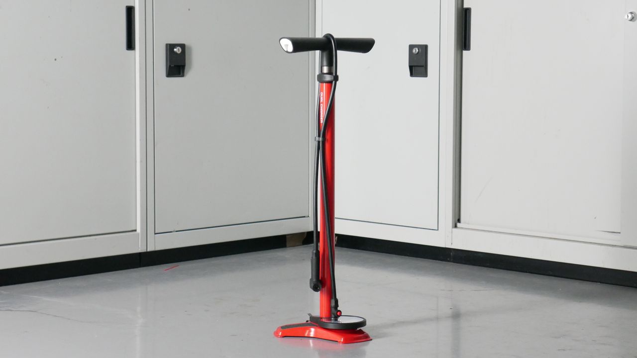 Trek Dual Chamber bike track pump in black set against a background of some workshop cabinets