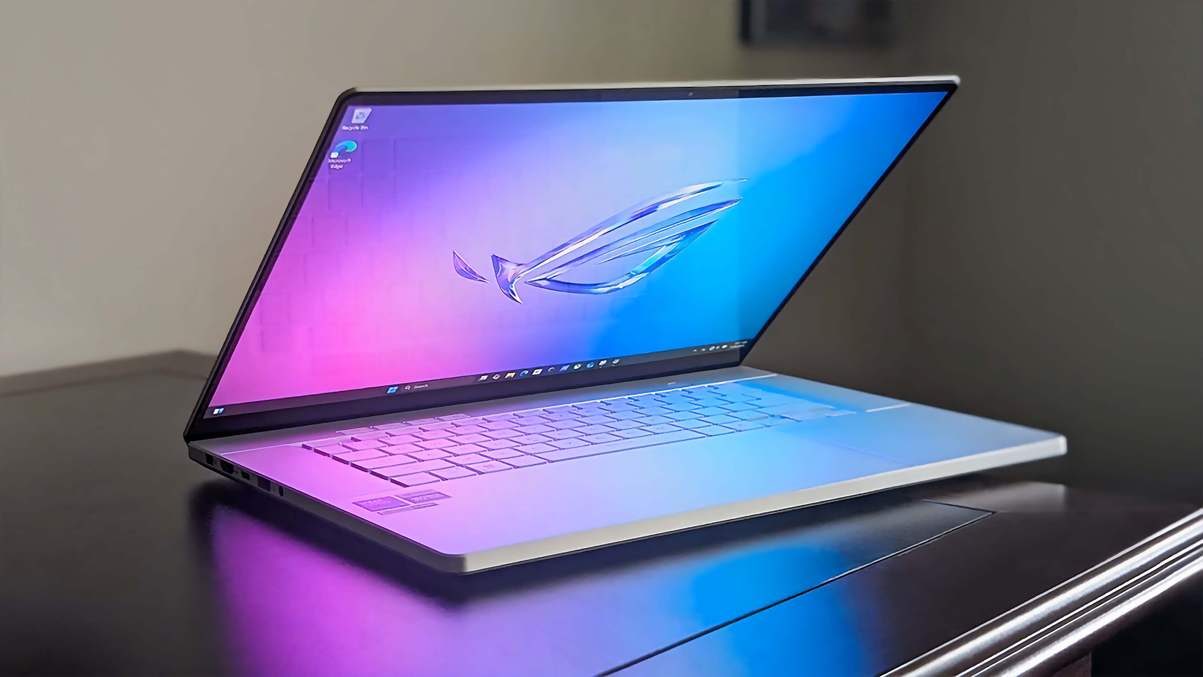 ASUS ROG Zephyrus G16 (GU605C, 2025) sitting on a desk in a dark room with the lid partially closed.