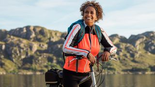 Woman bikepacking outdoors, leaning over handlebars of bike