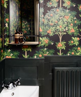 small bathroom with black paneling and radiator, wallpaper with orange trees on black background, mirror