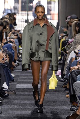 a model on the JW Anderson spring 2025 runway wearing moto boots with an oversize satin jacket