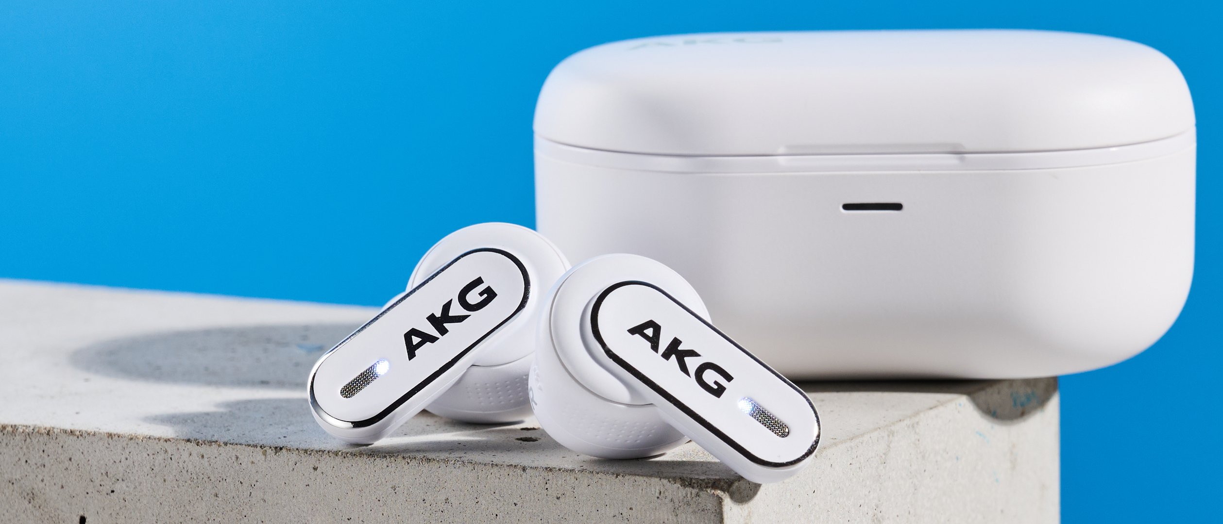the akg n5 hybrid earbuds by harman in white, shown in their charging case with accessories and without