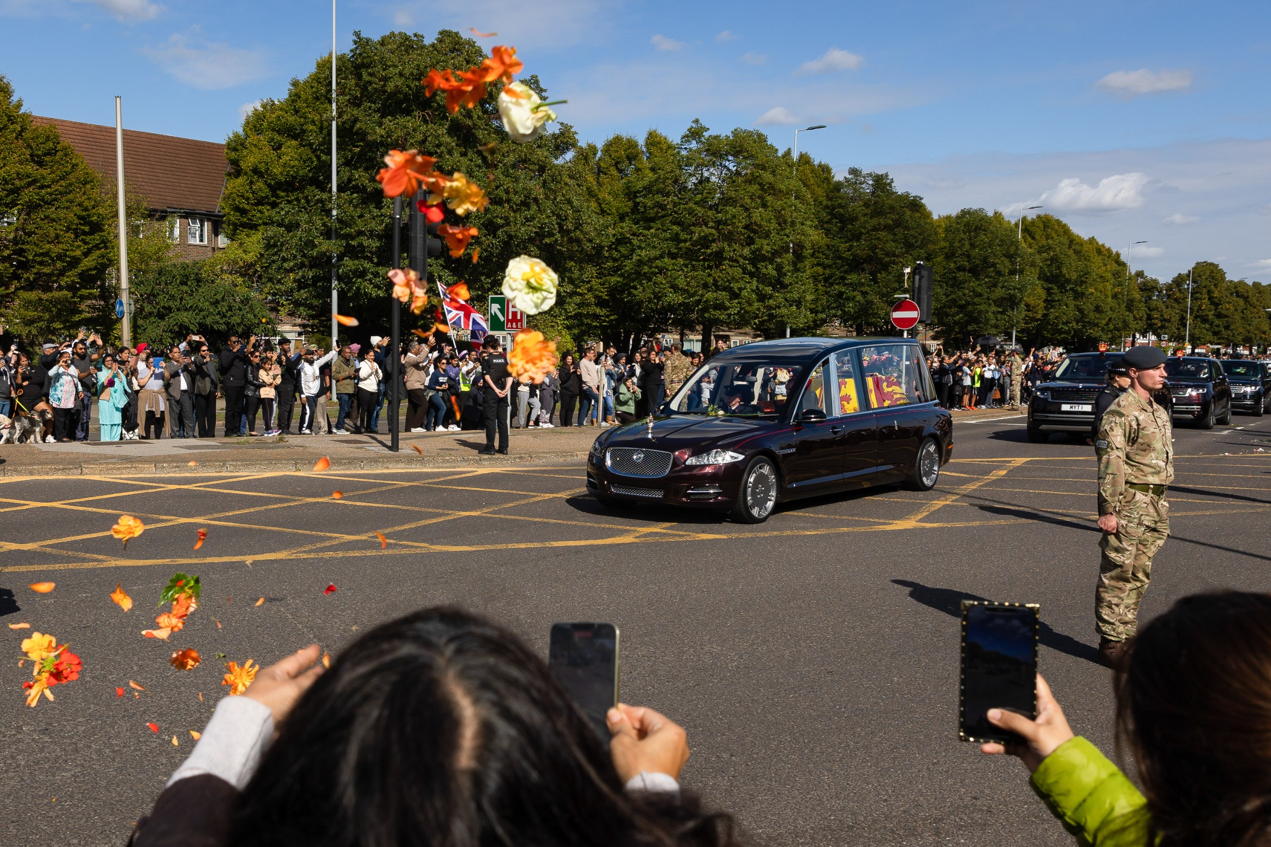 People throwing flowers into the street during Queen Elizabeth's funeral procession