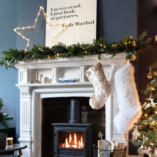 Dark navy painted living room with white fireplace and mantelpiece decorated with Christmas decorations and stockings