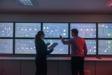 Tutor and student in front of monitors in ship's engine room simulator