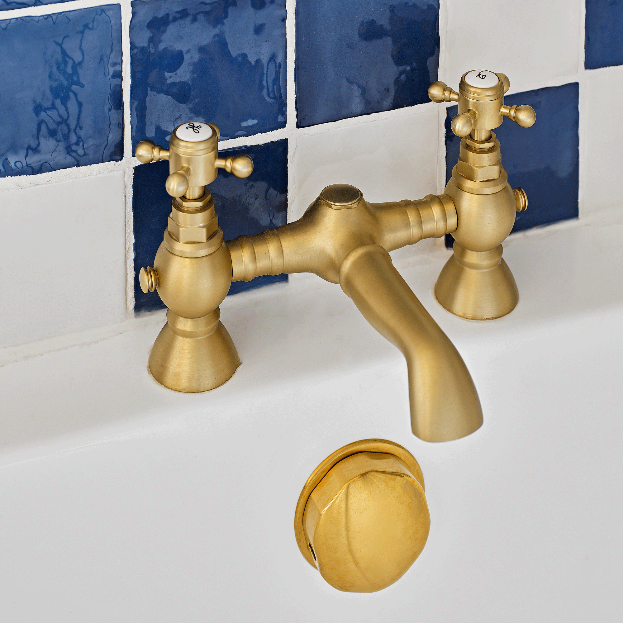close up of brass bath taps in a bathroom with blue and white wall tiles