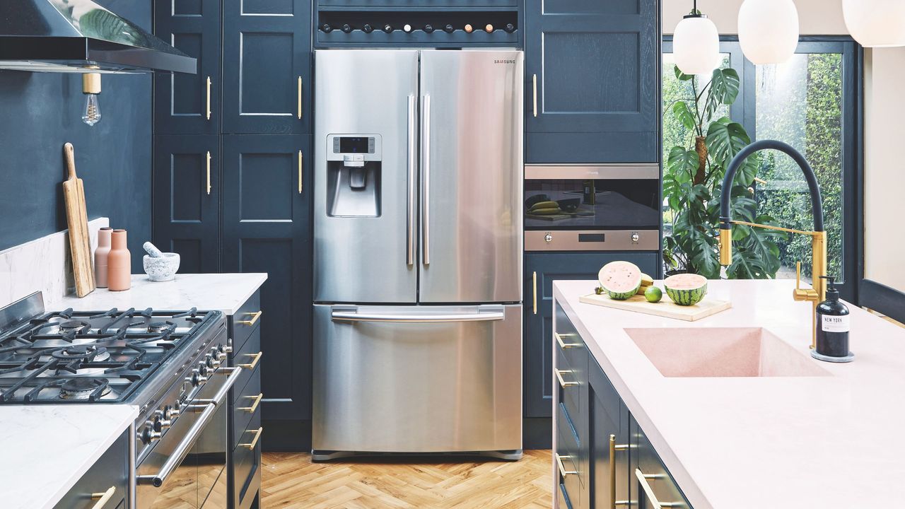 Large fridge freezeer in a kitchen with white worktops and blue cabinetry