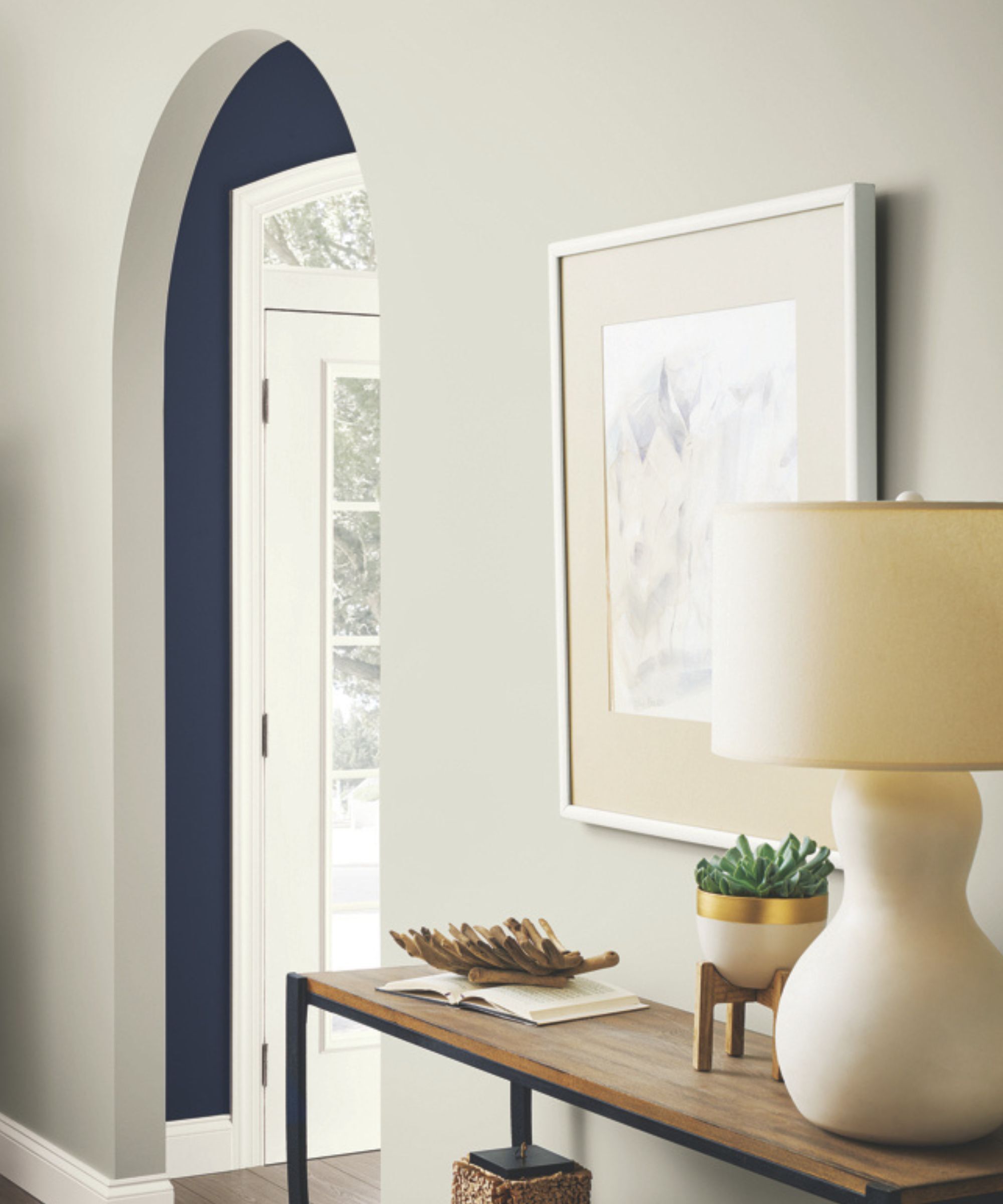 A hallway leading to another room, with an entryway table and a lamp. The walls are painted in Repose Gray by Sherwin Williams