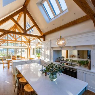 kitchen diner with exposed timber beams and a glazed gable and roof windows