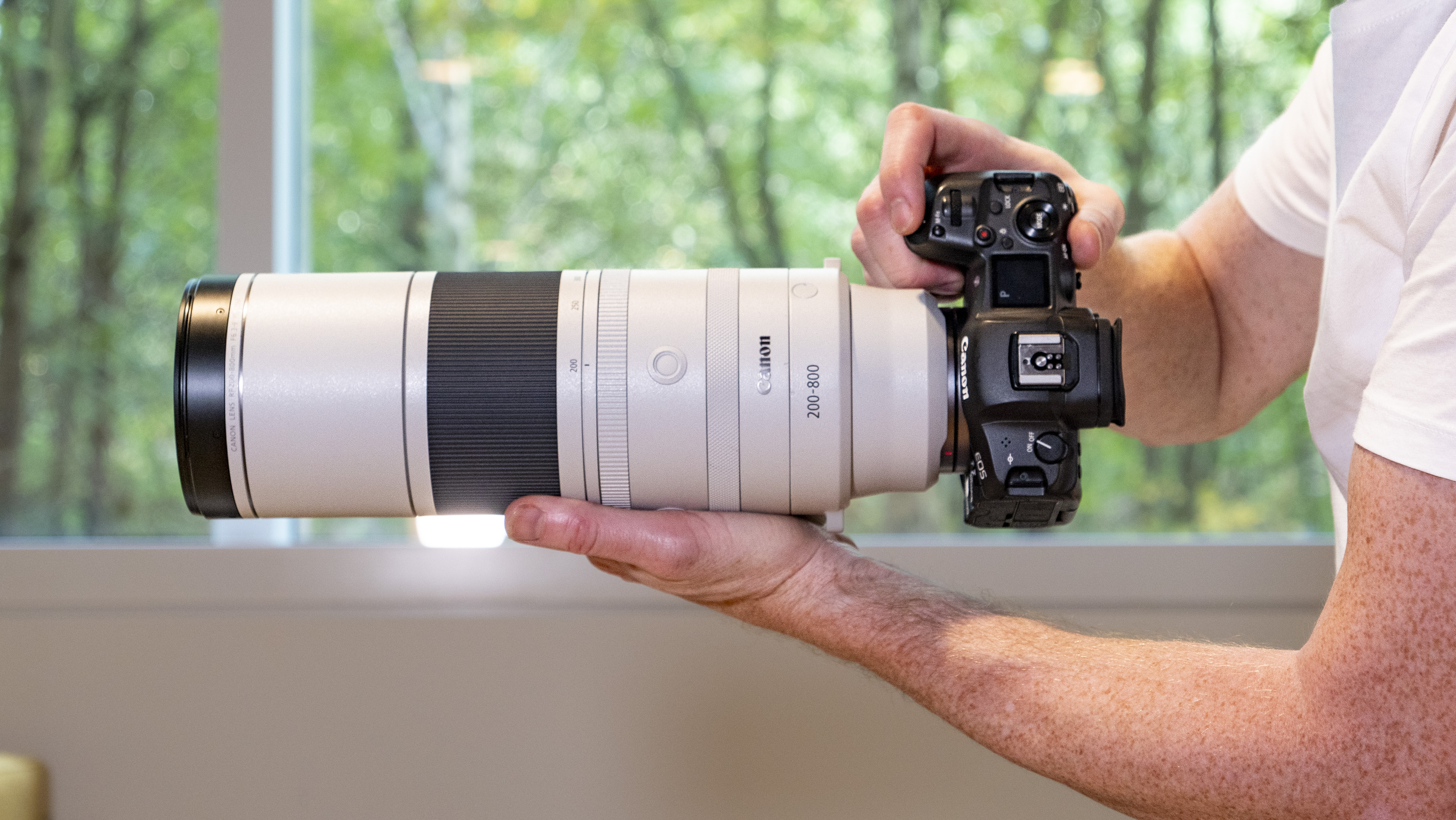 Canon RF 200-800mm F6.3-9 lens in the hand, mounted to a Canon EOS R5