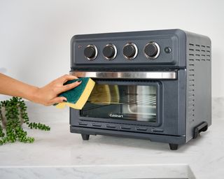 Christina Chrysostomou using sponge to wipe down Cusinart Air Fryer Toaster Oven appliance