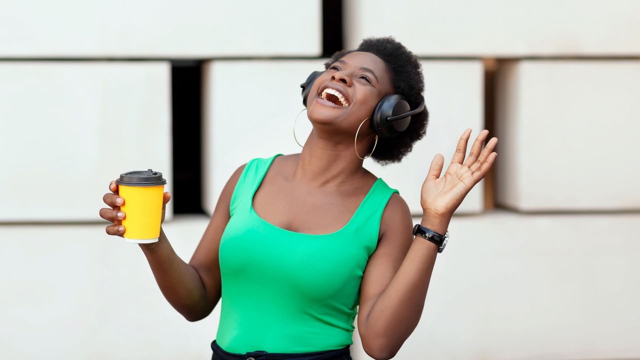 Image shows woman smiling and holding coffee cup