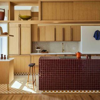 Wooden kitchen with island covered in burgundy square tiles