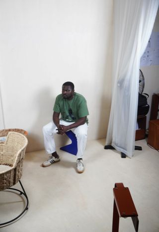 Nifemi Marcus-Bello at his studio wearing a green shirt and white trousers.