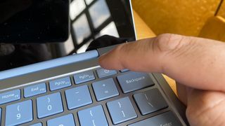person about to turn on a laptop at the power button