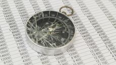 A smashed compass on top of financial paperwork.