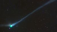 A photo of the green comet with a long tail in the night sky