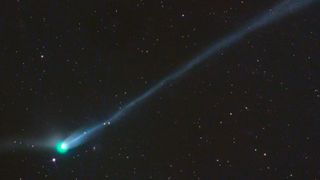 A photo of the green comet with a long tail in the night sky