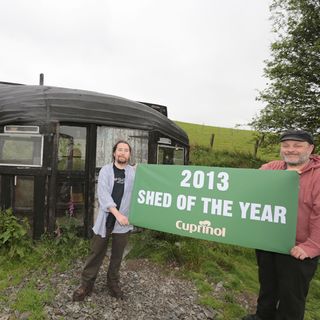 2 man holding a shed of the year banner