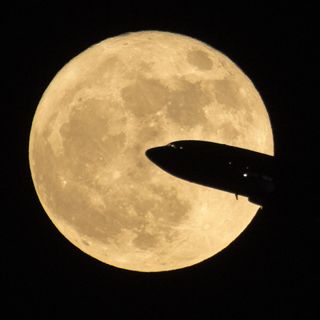 An airplane crosses the supermoon full moon of Dec. 3, 2017 as seen near Ronald Reagon National Airport in Washington, D.C.