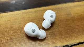 The Sony WF-C700N wireless earbuds in white, on a wooden background