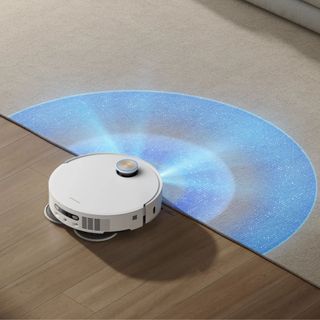 White Dreame X50 robot vacuum on hardwood floor with rays of light coming out of it