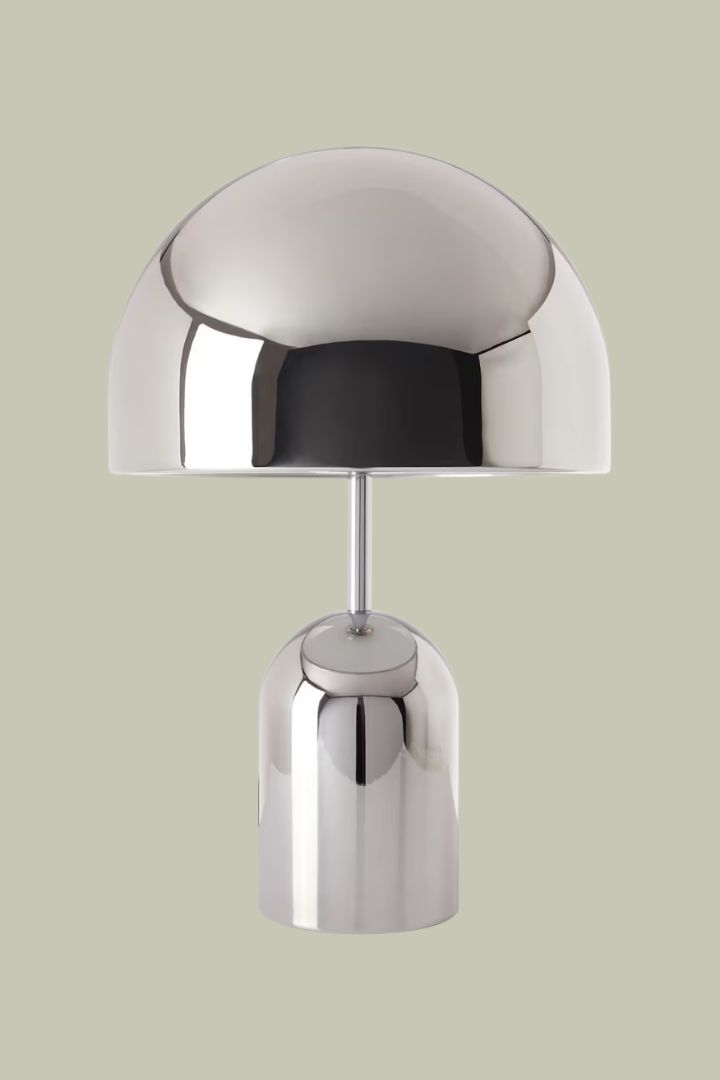 A mushroom-shaped chrome lamp against a green background.