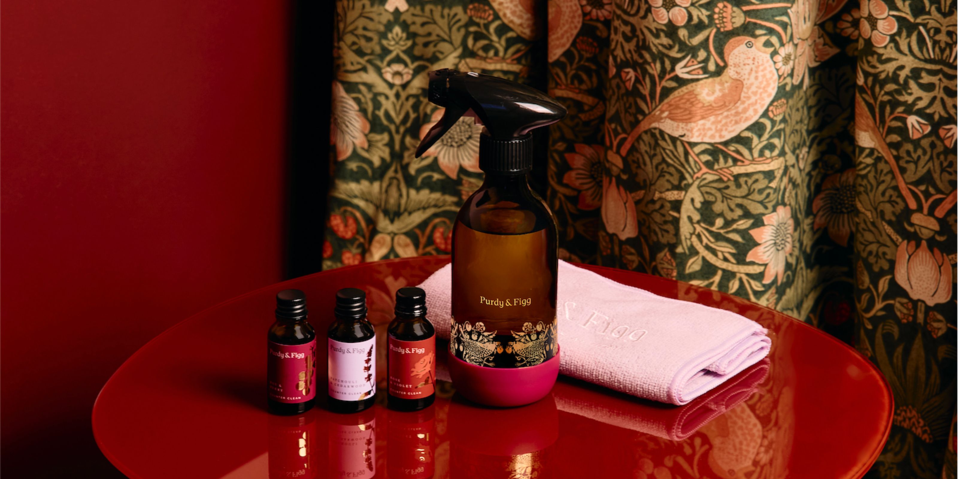 William Morris' limited edition collection with Purdy and Figg, featuring a bottle and three refill scents placed on a red table