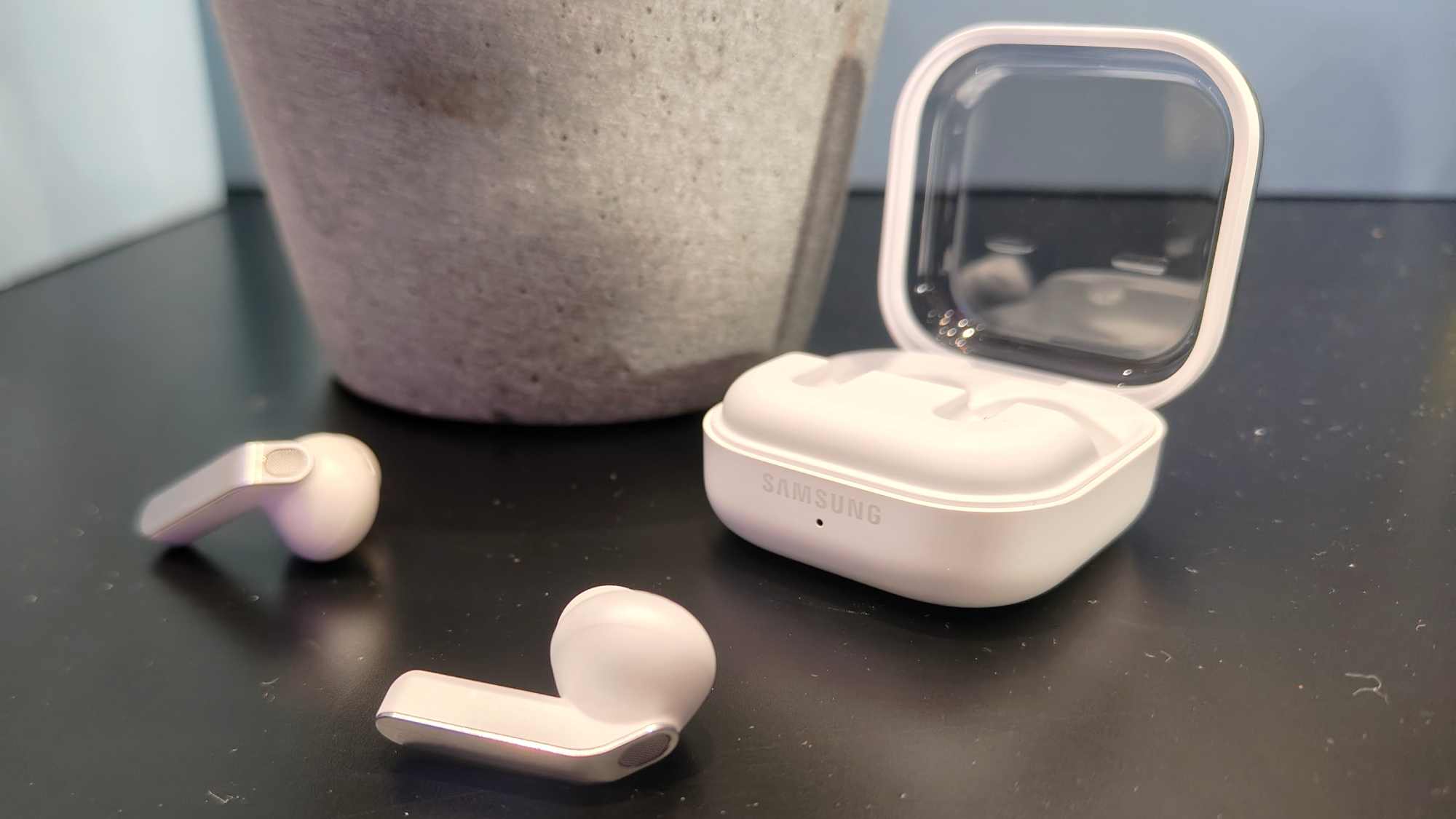 The Samsung Galaxy Buds 4 Pro, next to their charging case.