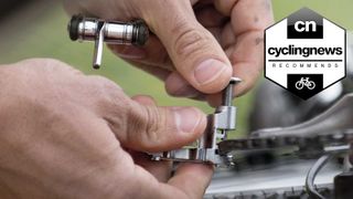 A close up of someone's hands using a multi tool to split a chain